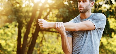 Man stretching arm outdoors